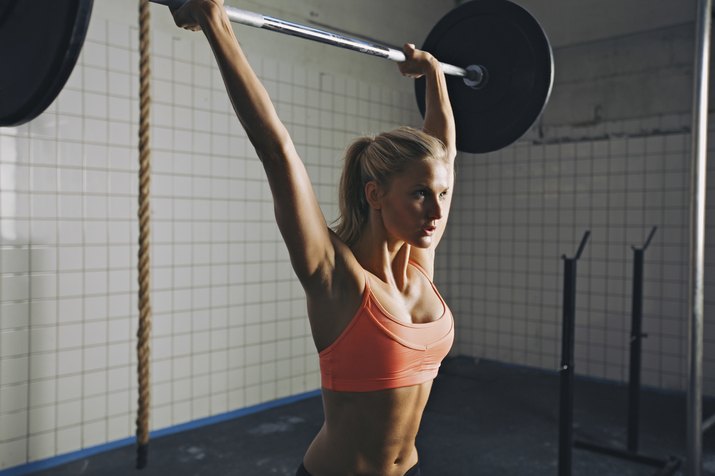Woman doing gym barbell lifting