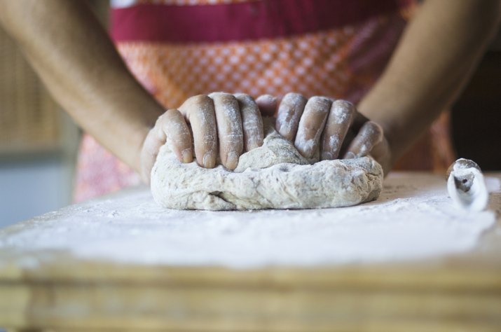 Mixed race woman kneading dough in kitchen