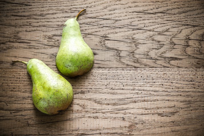 Halves of green pear on the wooden background