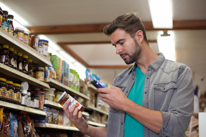 Young man checking product on smartphone in health food store