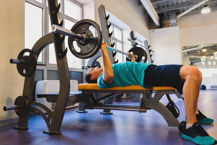 Young Man In Gym Exercising Chest On The Bench Press