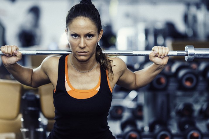 Woman exercising in gym with olympic barbell weights