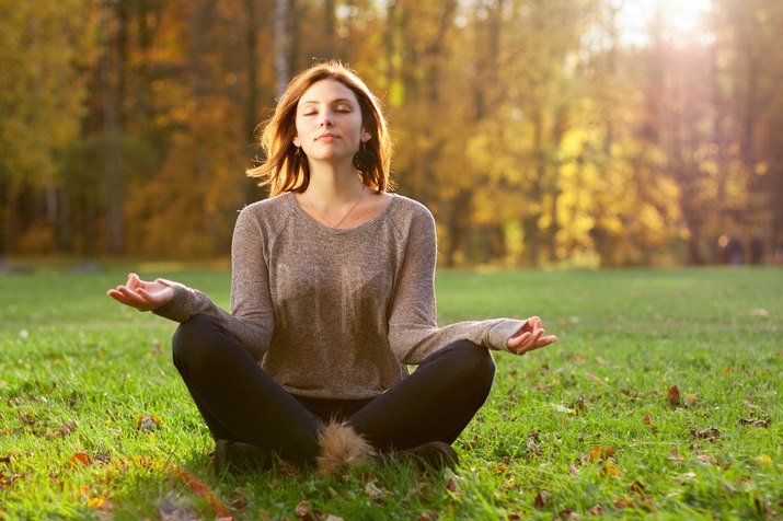 Young girl meditating in autumn park