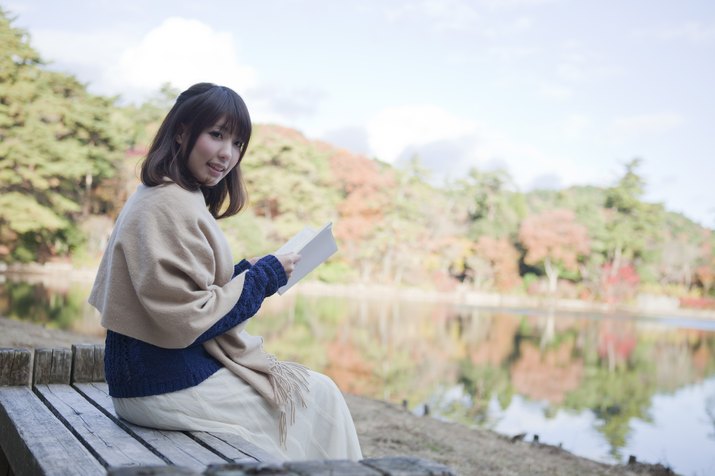 Japanese woman reading next to a lake