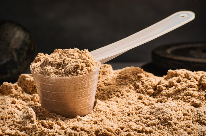 Scoop of whey protein on black background for muscle building diet
