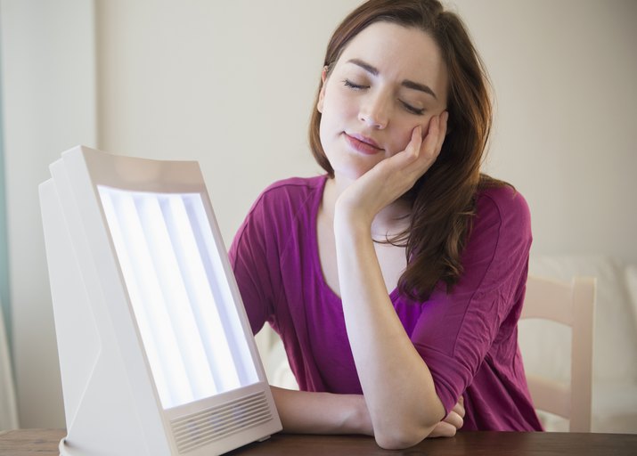 Woman sitting by light therapy box