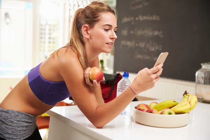 Woman Wearing Gym Clothing Looking At Mobile Phone