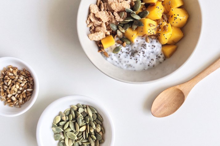 A breakfast bowl with mango chunks, chia pudding and pumpkin seeds