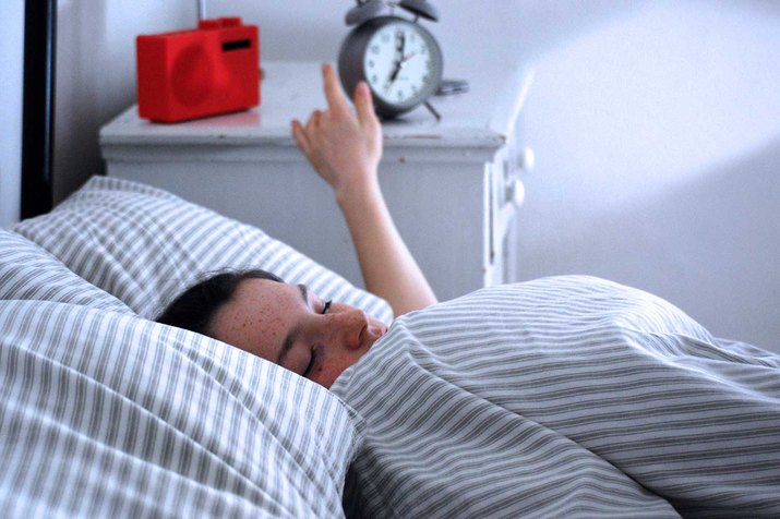 Woman turning off morning alarm.