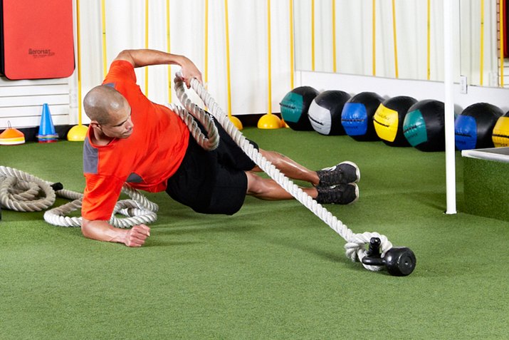 Man doing Side Plank With Rope Pull with the battle ropes