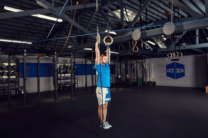 Man demonstrates a high ring banded muscle-up in a CrossFit gym
