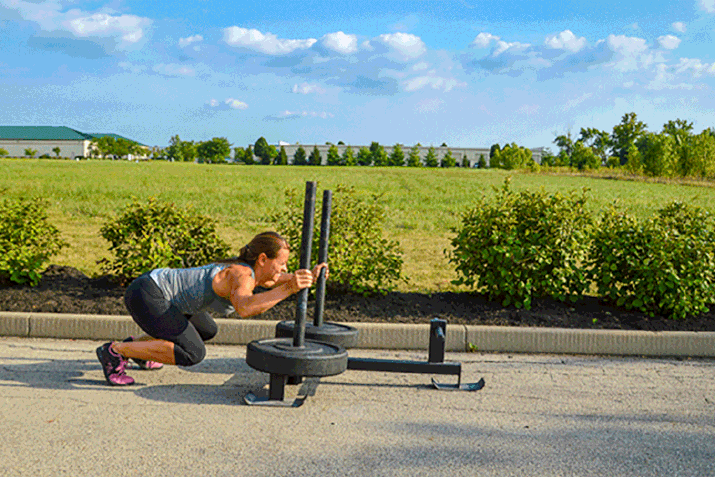 woman doing a broad jump with a Prowler sled