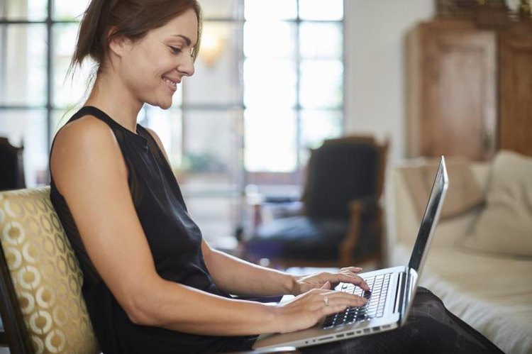 Beautiful woman relaxing at home with laptop. Lifestyle shot in real location, Spain.