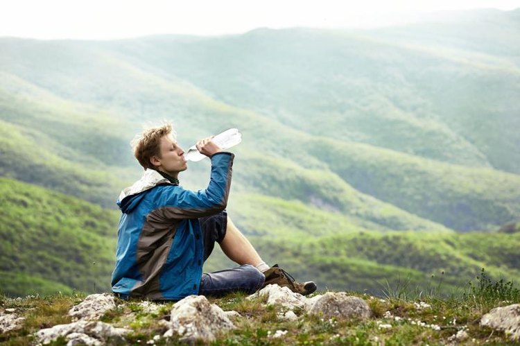 Man on the edge of the hill in Carpathian Mountains drinking alkaline water.