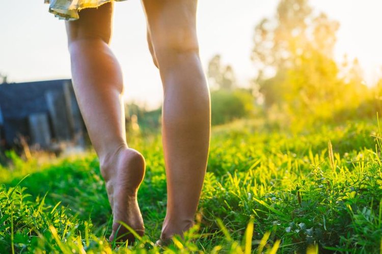 A woman walking on the grass in the sunset on fresh green grass.