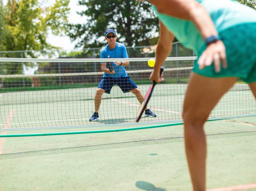 Mature Adult Couple Playing Pickleball on a Bright Summer Day after doing a pickleball warmup