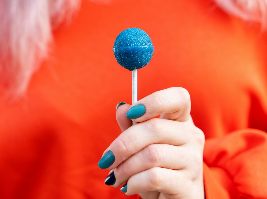 woman holding a bright blue lollipop