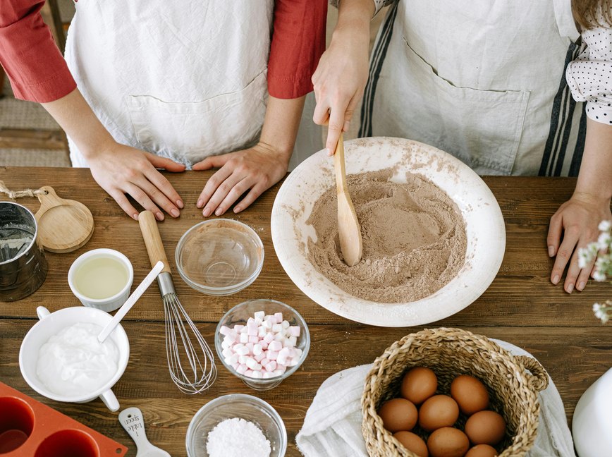 an overhead photo of two people baking in a kitchen using canola oil, a type of seed oil