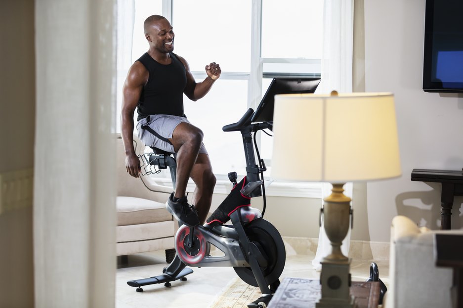 black man enjoying the benefits of stationary bike workouts at home in her living room